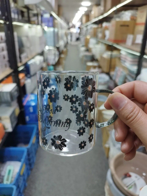 ماگ پیرکس دستهدار طرح گل بابونه مشکی در دست