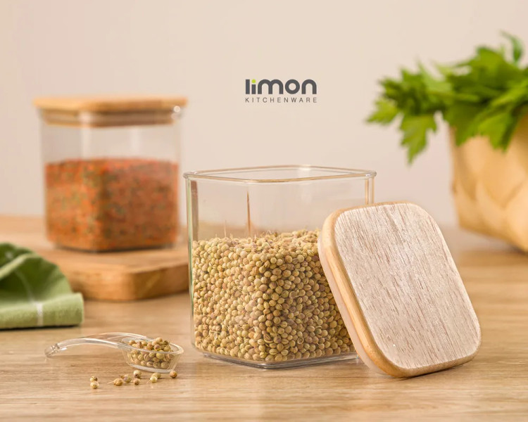 بانکه ادویه چهارگوش شفاف سارینا لیمون با در چوبی و پیمانه پلاستیکی روی میز آشپزخانه
